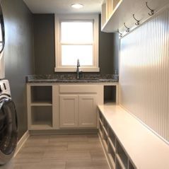 A laundry room with a washer and dryer , sink , and bench.