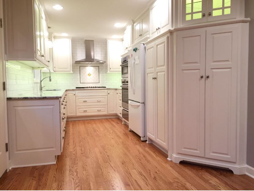 A kitchen with white cabinets and hardwood floors