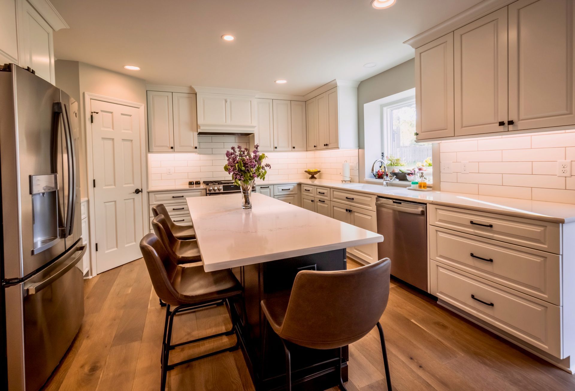 A kitchen with white cabinets , stainless steel appliances , and a large island.