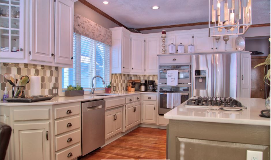 A kitchen with white cabinets , stainless steel appliances , and a large island.