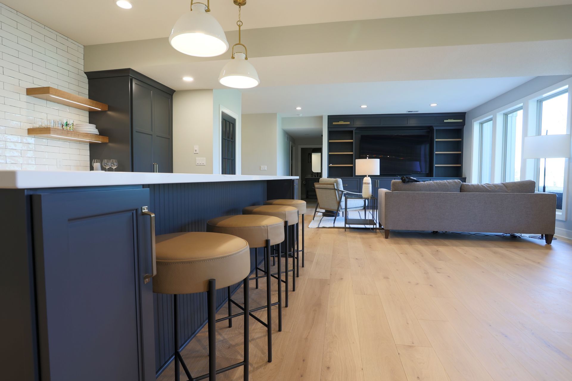 A kitchen with a bar and stools in a living room.