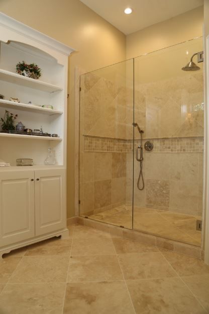 A bathroom with a walk in shower and a glass door.