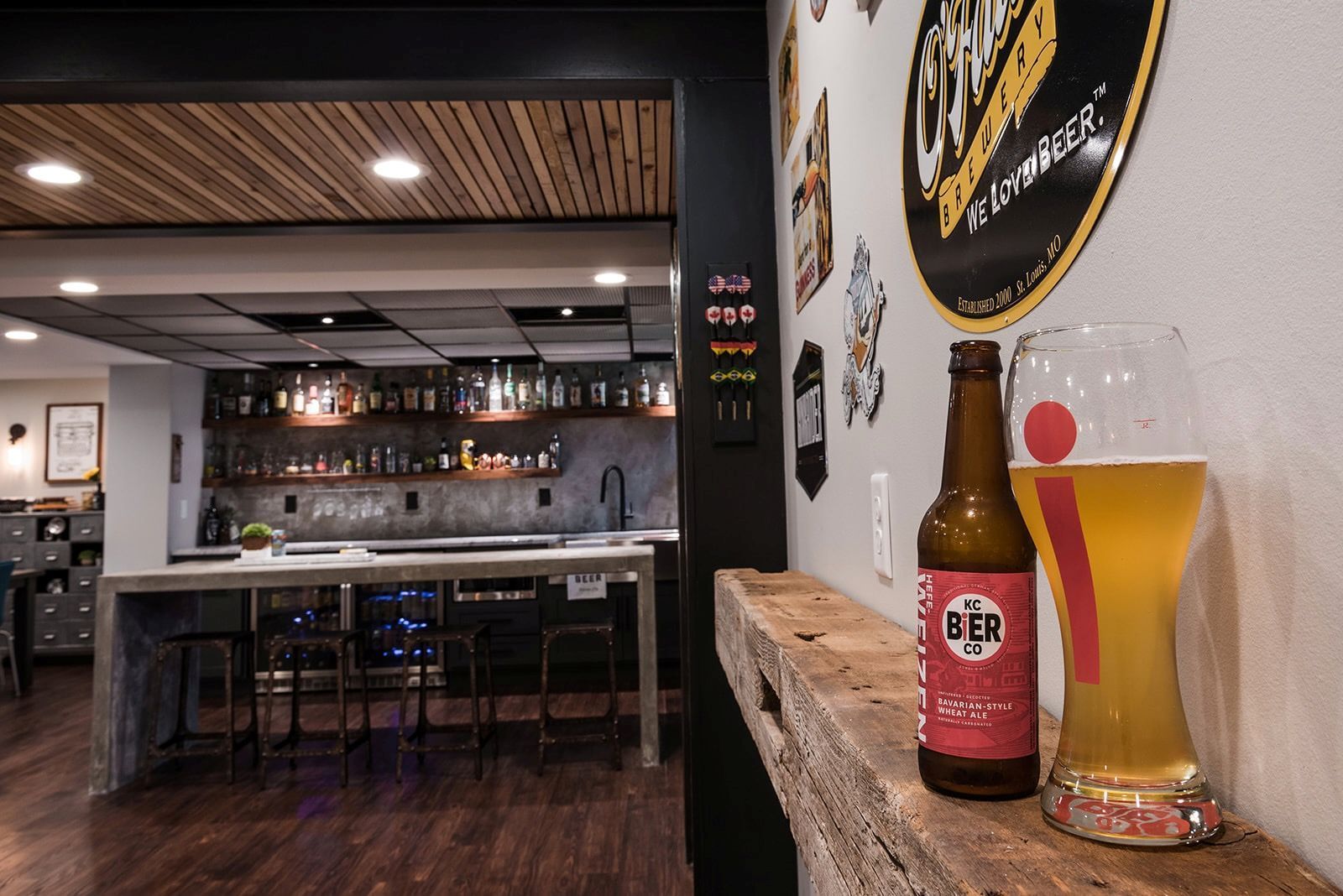 A bottle of beer and a glass of beer are on a wooden shelf.
