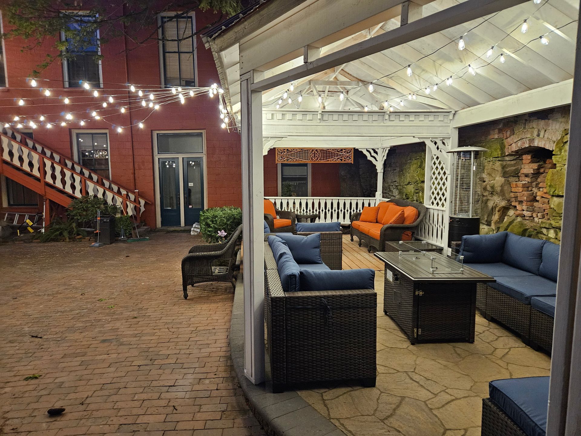 A patio with a gazebo and lots of furniture and lights.