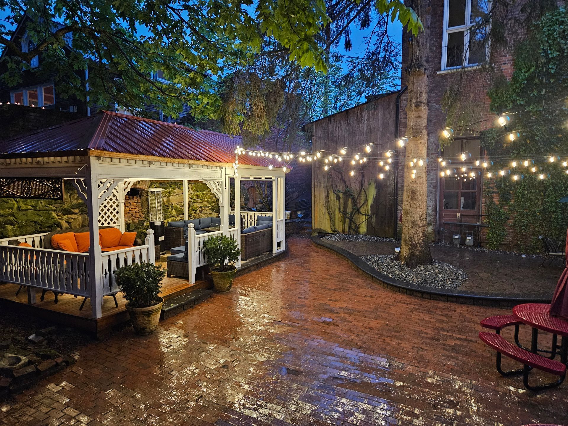 A gazebo is lit up at night in a backyard.