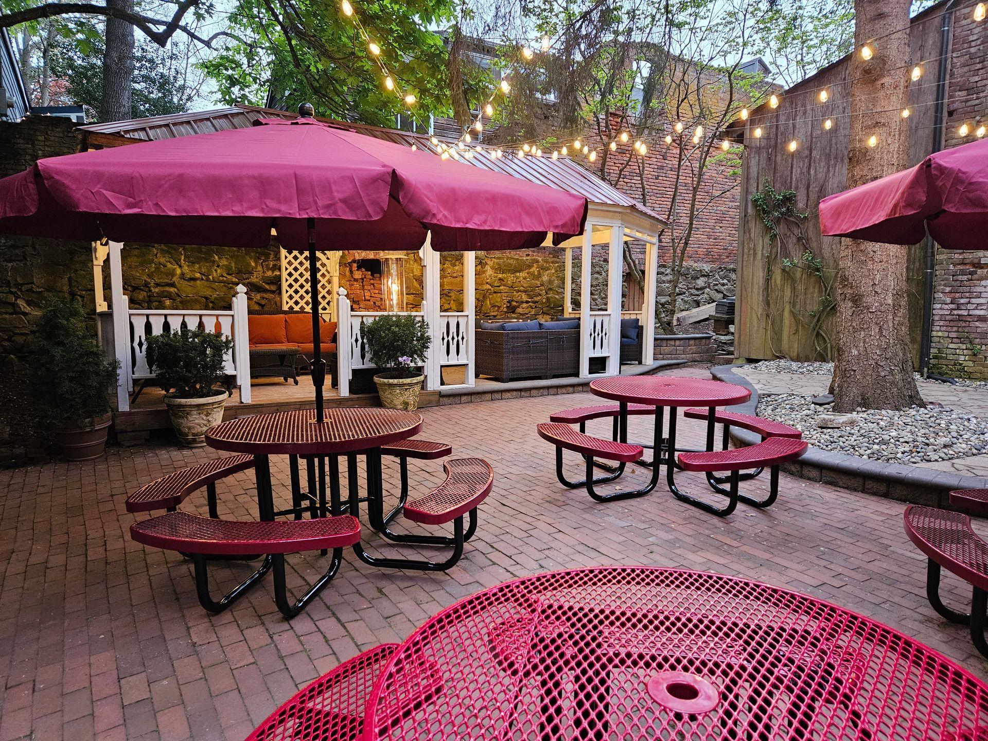A patio with red picnic tables and umbrellas.