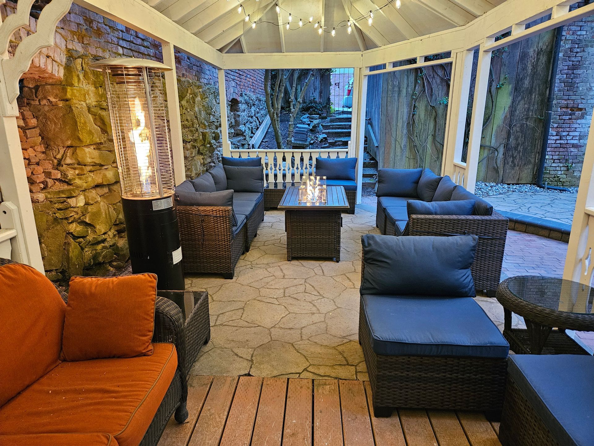 A gazebo with a lot of furniture and a table with candles on it.