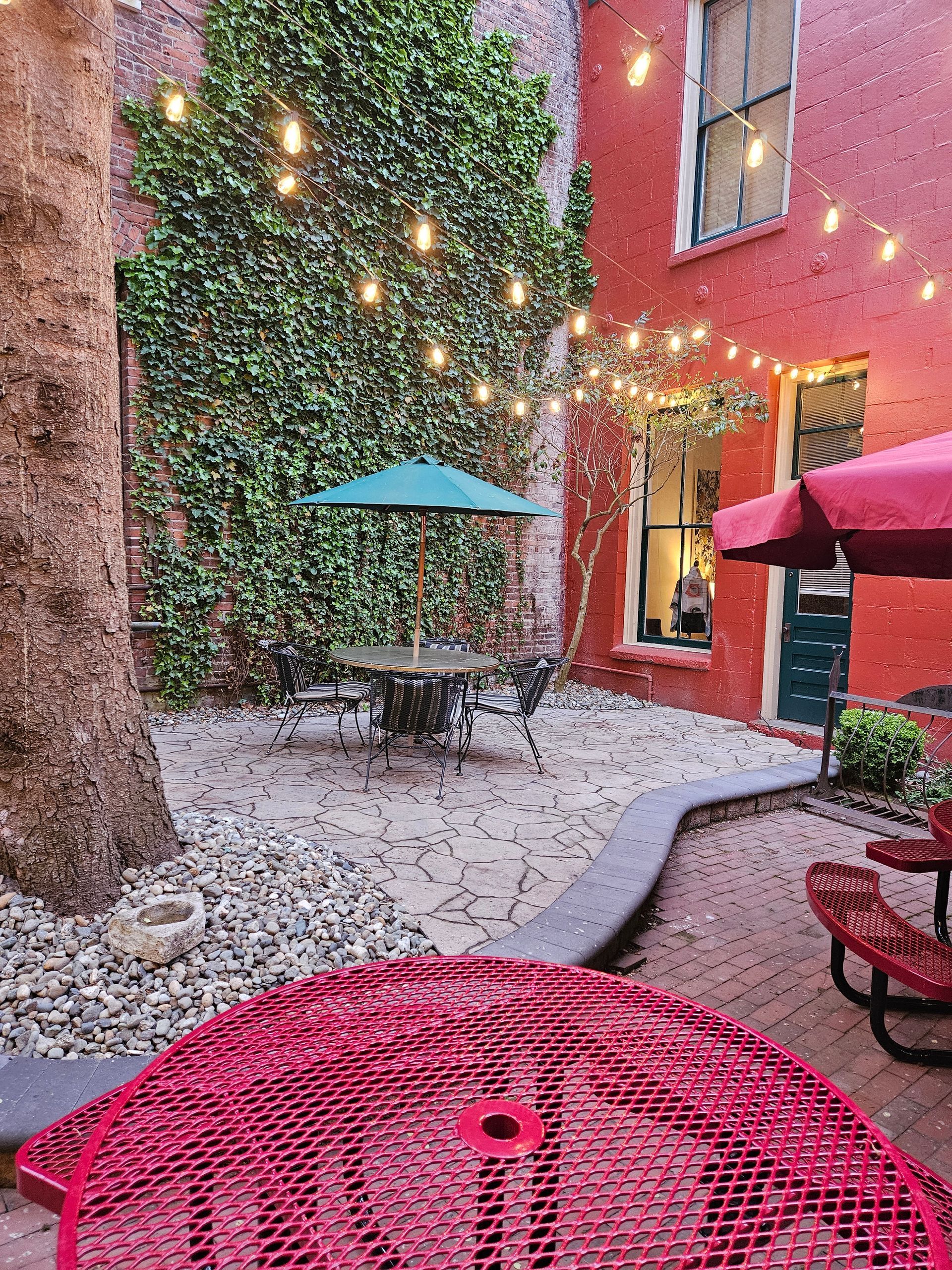 There are tables and chairs in the courtyard with umbrellas.