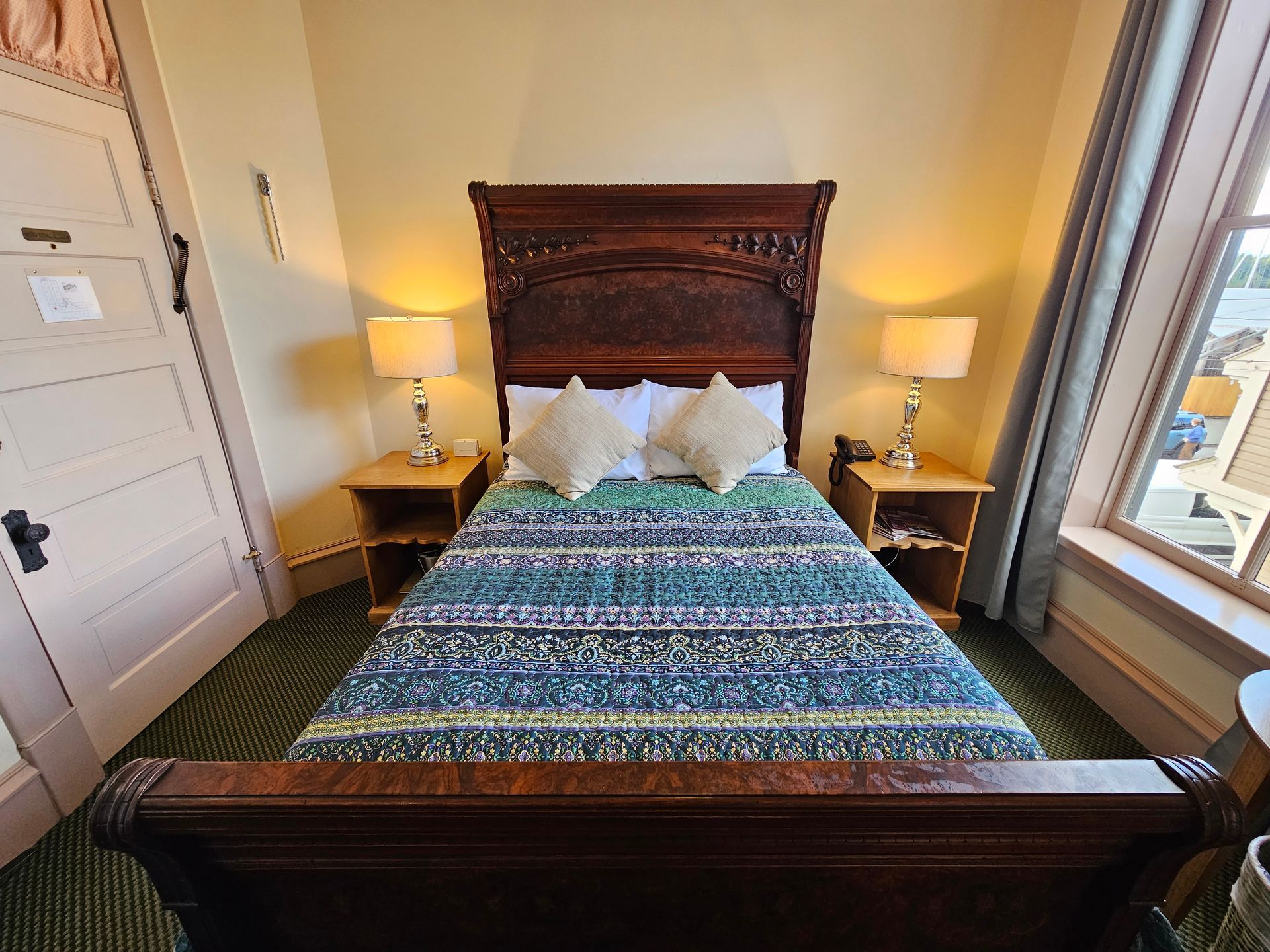 A hotel room with a bed , nightstands , lamps and a window.