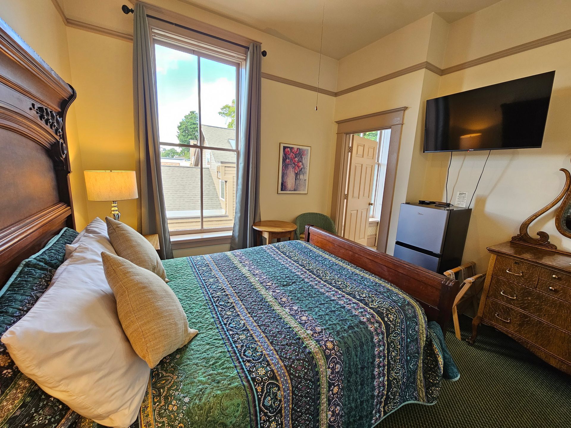 A bedroom with a bed , dresser , television and window.