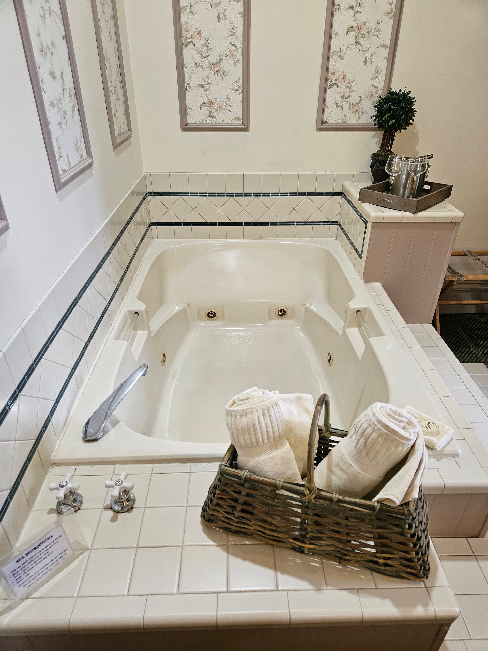 A bathroom with a jacuzzi tub and a basket of towels on the counter.