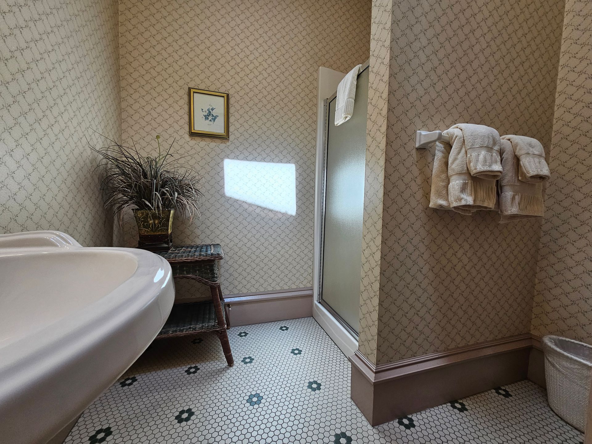 A bathroom with a sink , shower , and towels hanging on the wall.