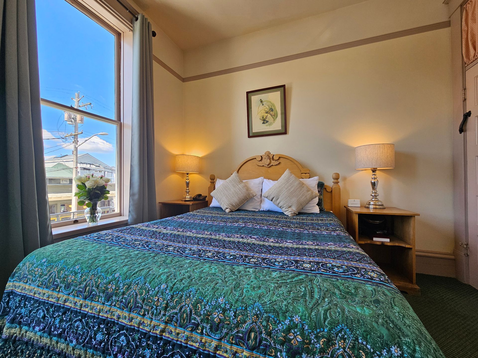 A hotel room with a bed , nightstands , lamps and a large window.