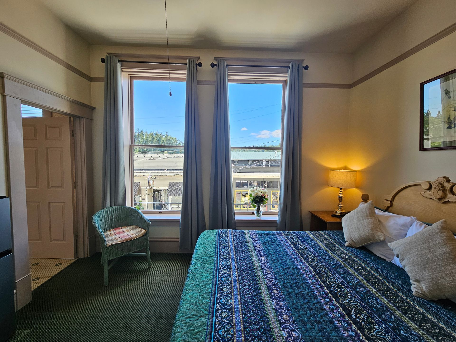 A hotel room with a king size bed and two windows.