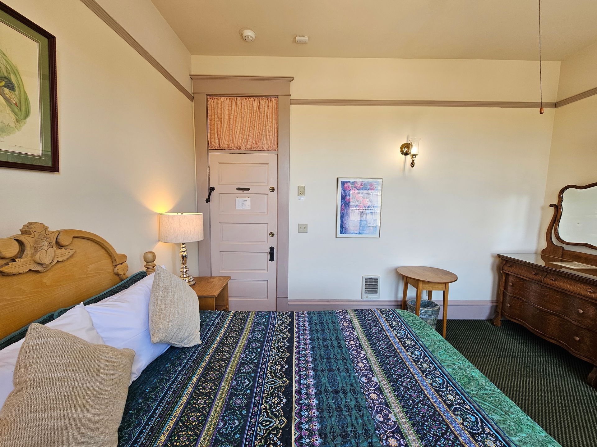 A bedroom with a king size bed , dresser and mirror.