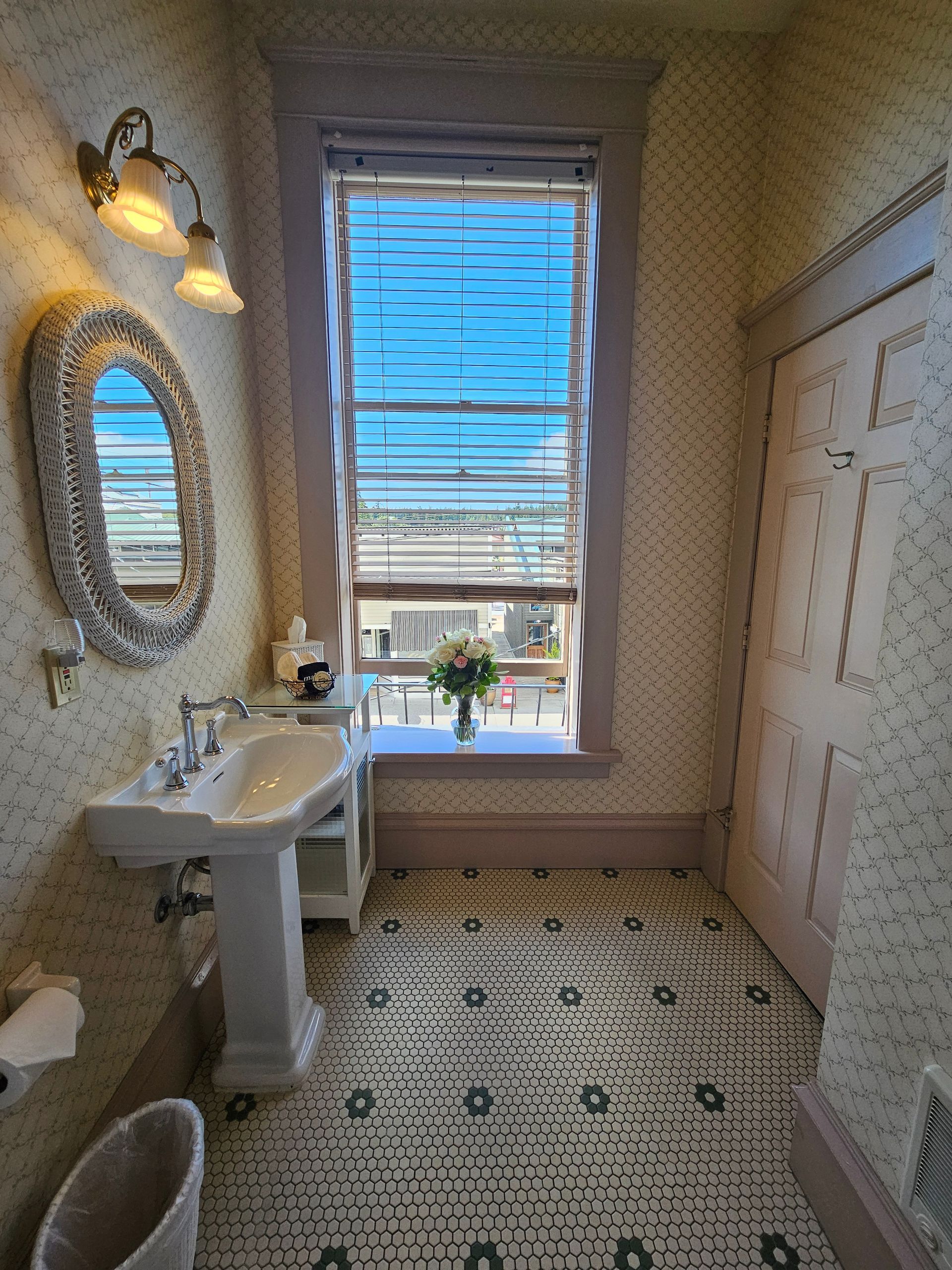 A bathroom with a sink , mirror , and window.