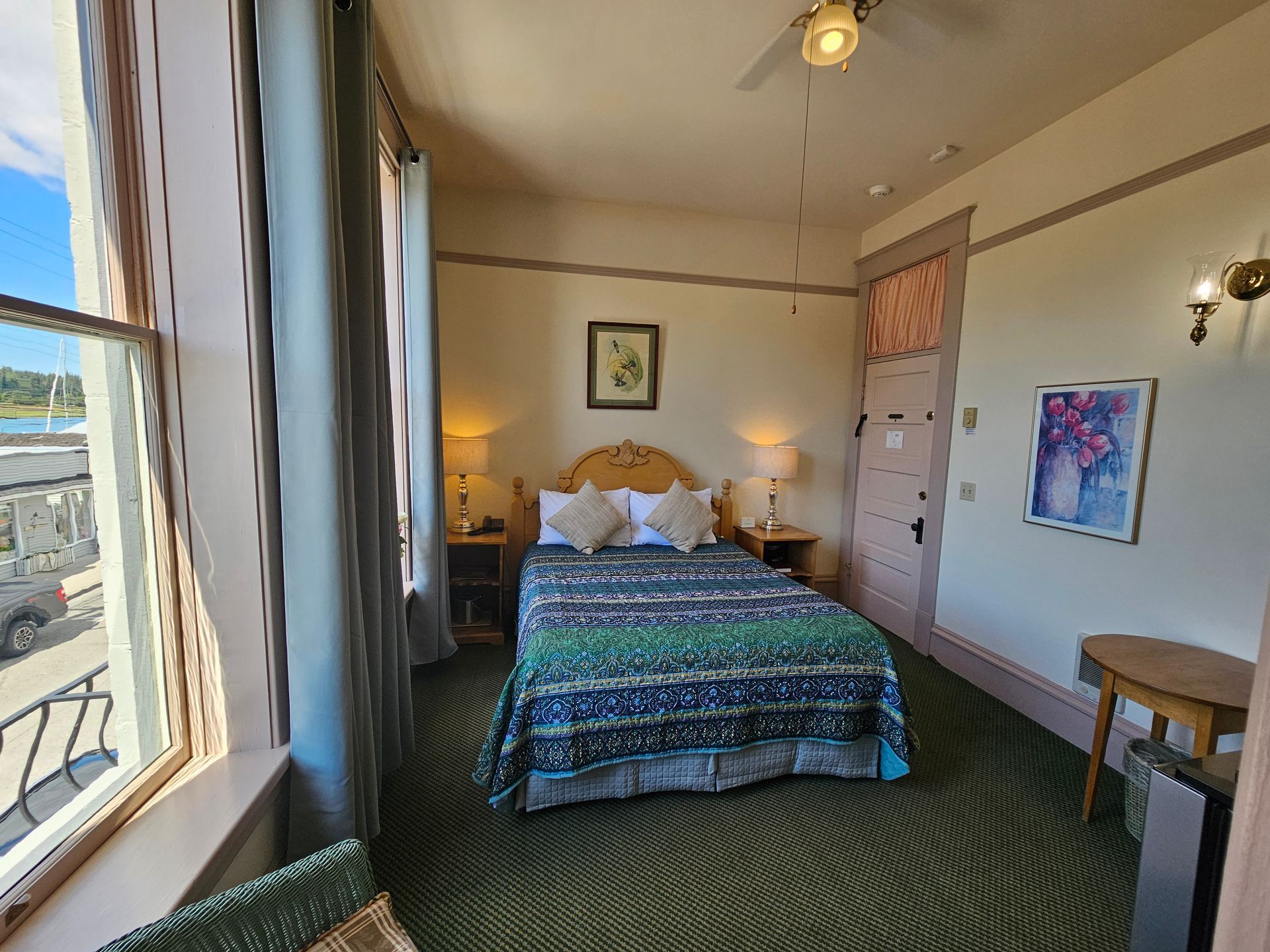 A hotel room with a bed , a table , and a window.