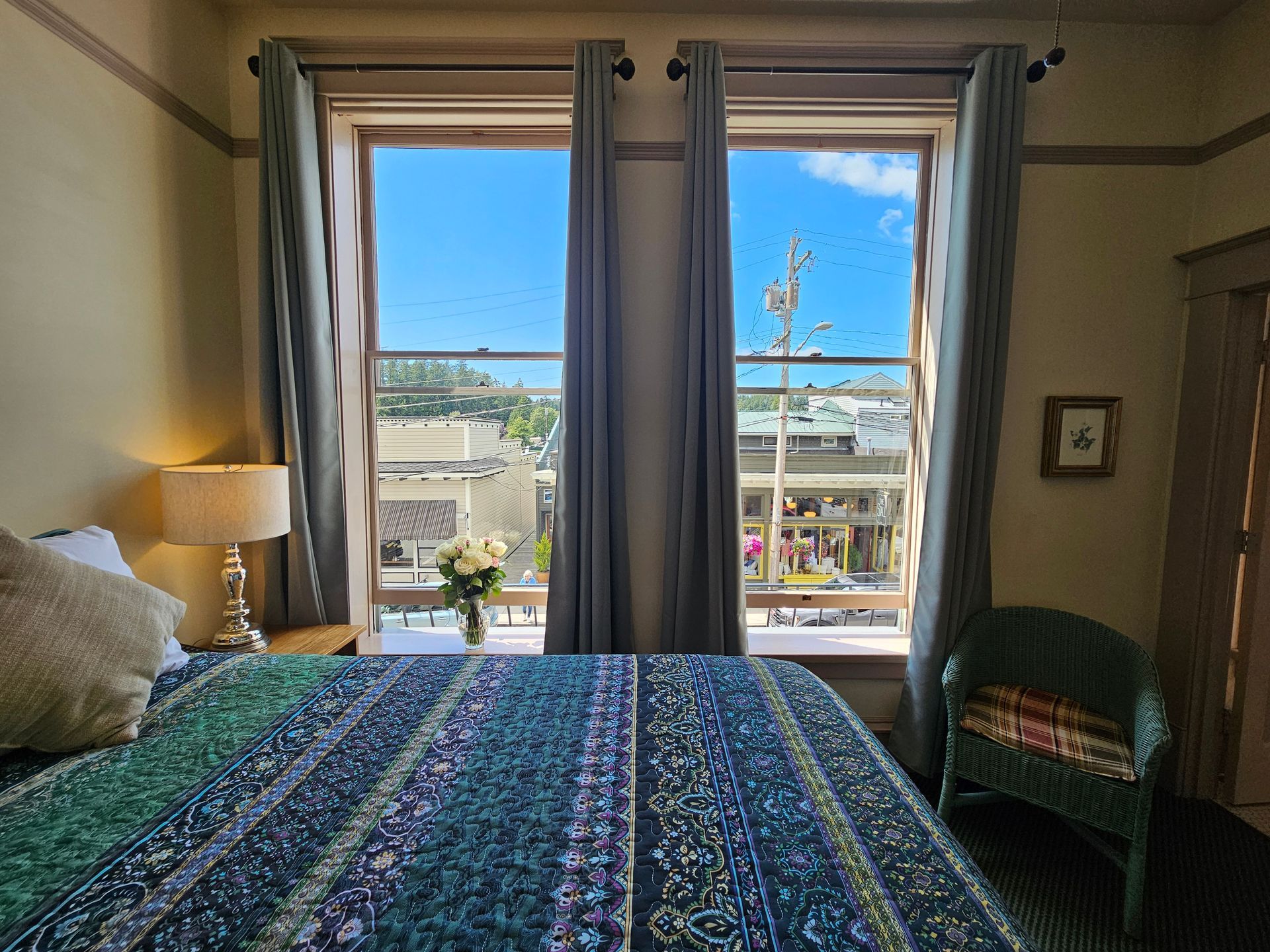 A bedroom with a bed , chair , lamp and two windows.