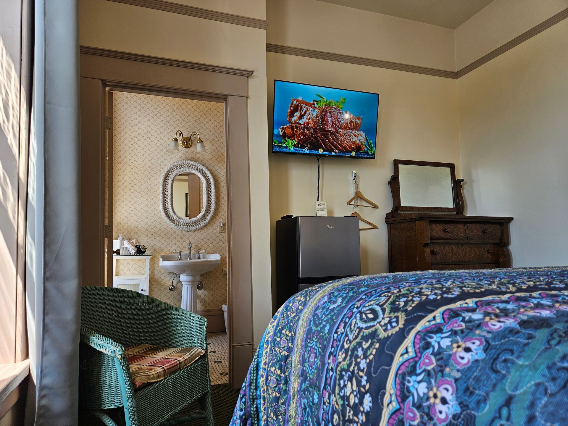 A bedroom with a bed , chair , television , sink and mirror.