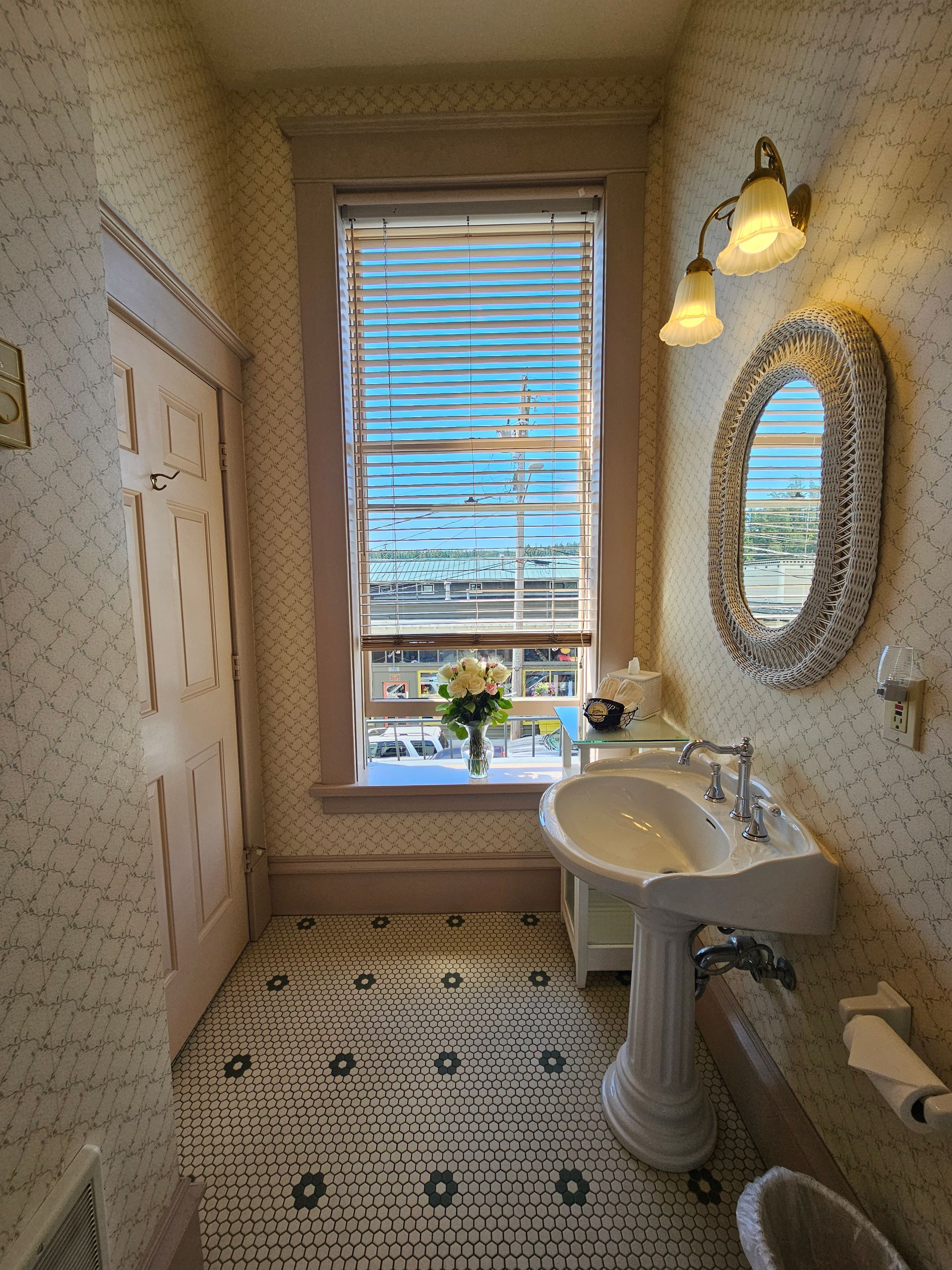 A bathroom with a sink , mirror and window.