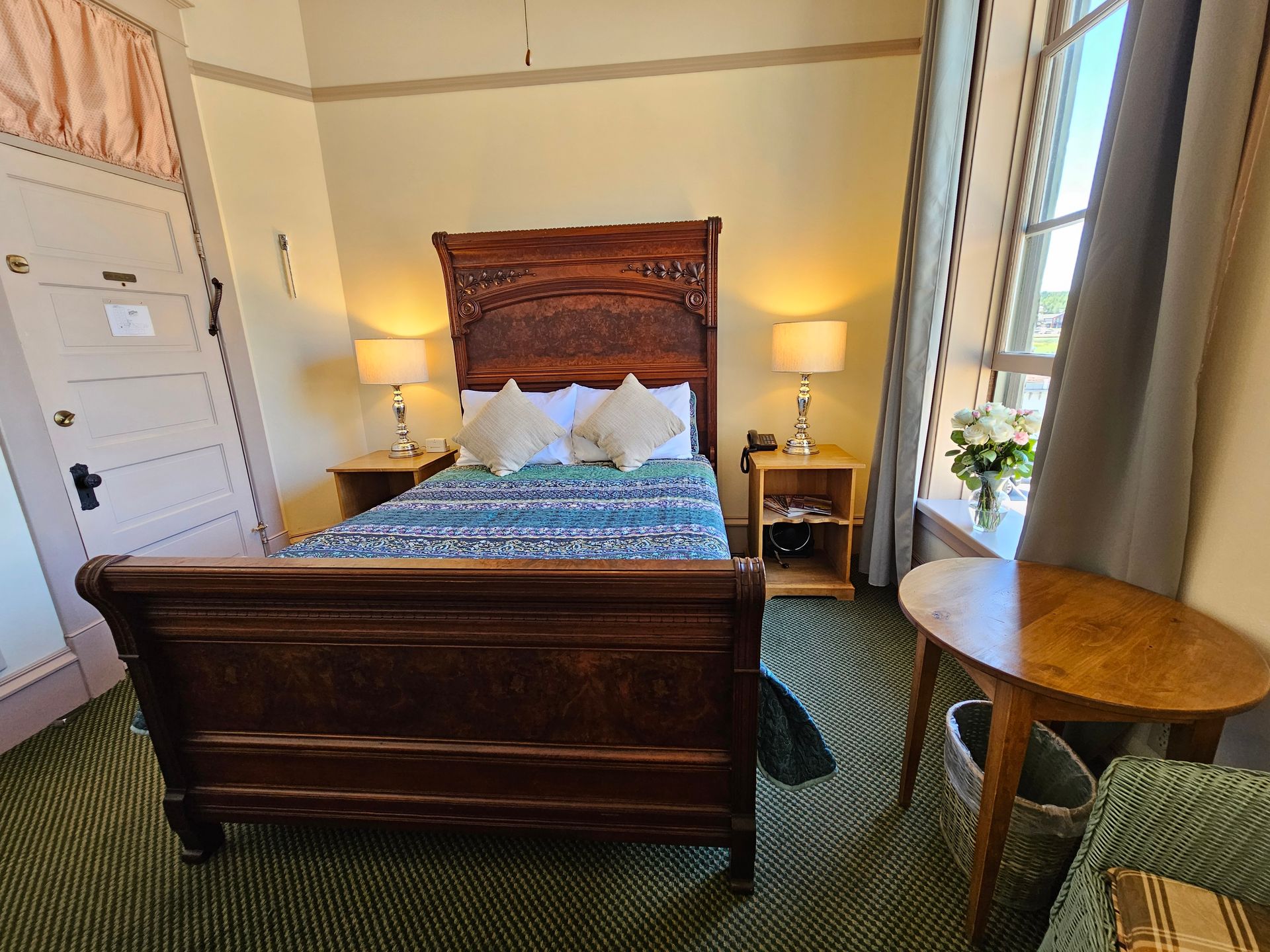 A bedroom with a bed , table , chair and window.