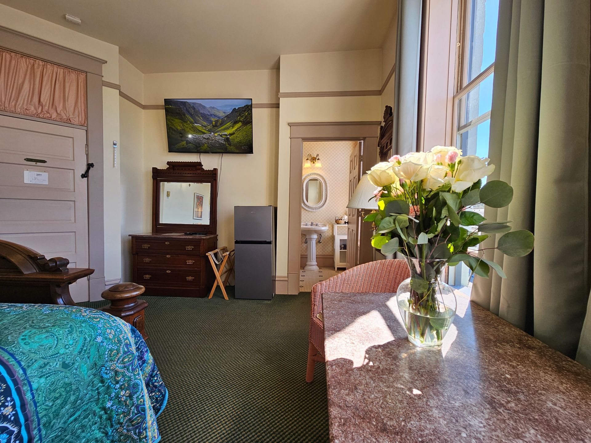 There is a vase of flowers on a table in a hotel room.