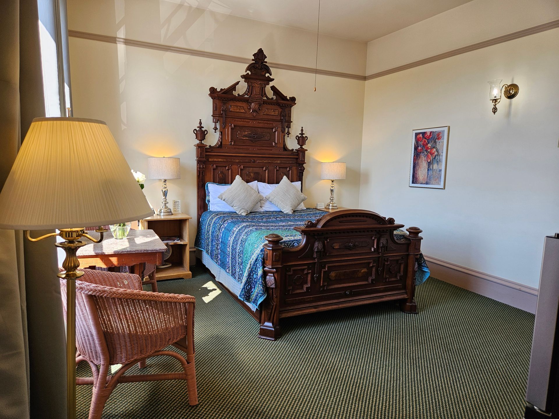 A hotel room with a bed , chair , lamp and table.