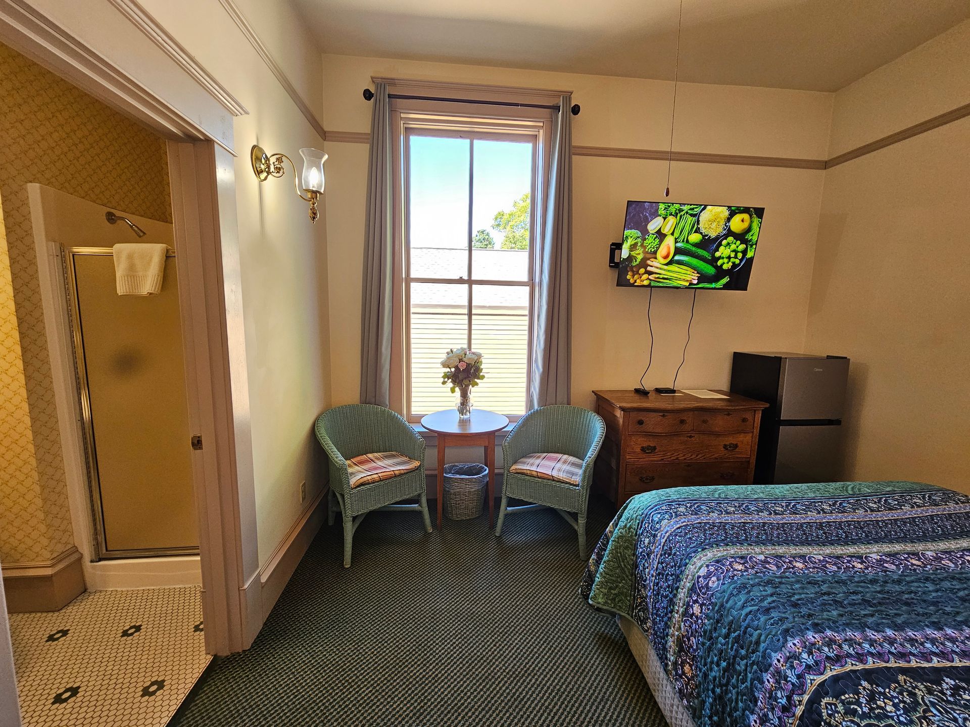 A hotel room with two beds , two chairs , a table and a television.