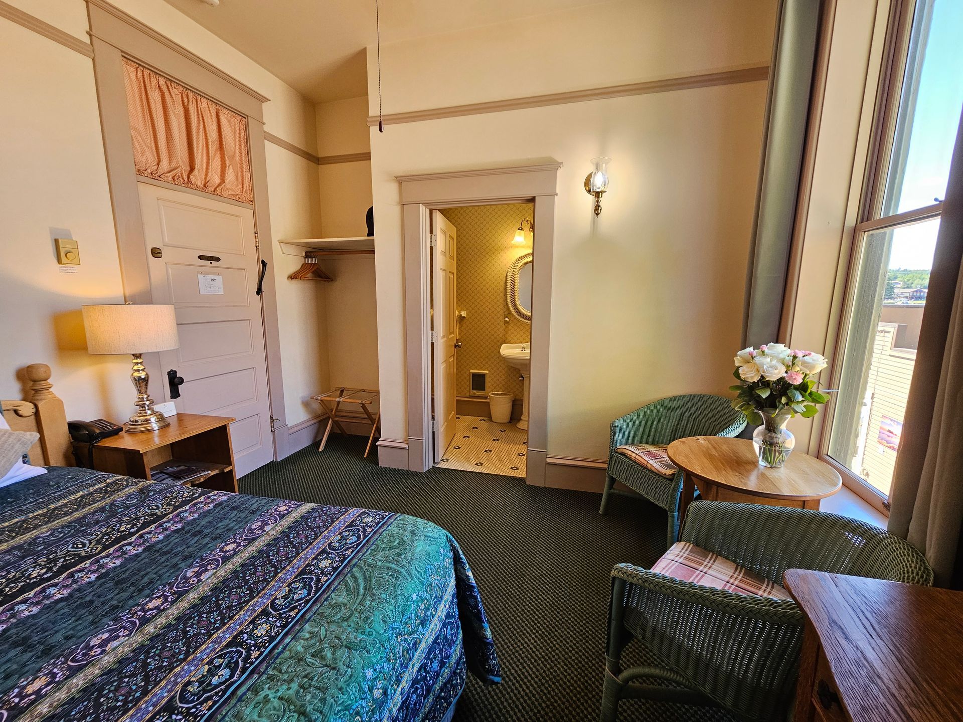 A hotel room with a bed , chairs , a table and a window.