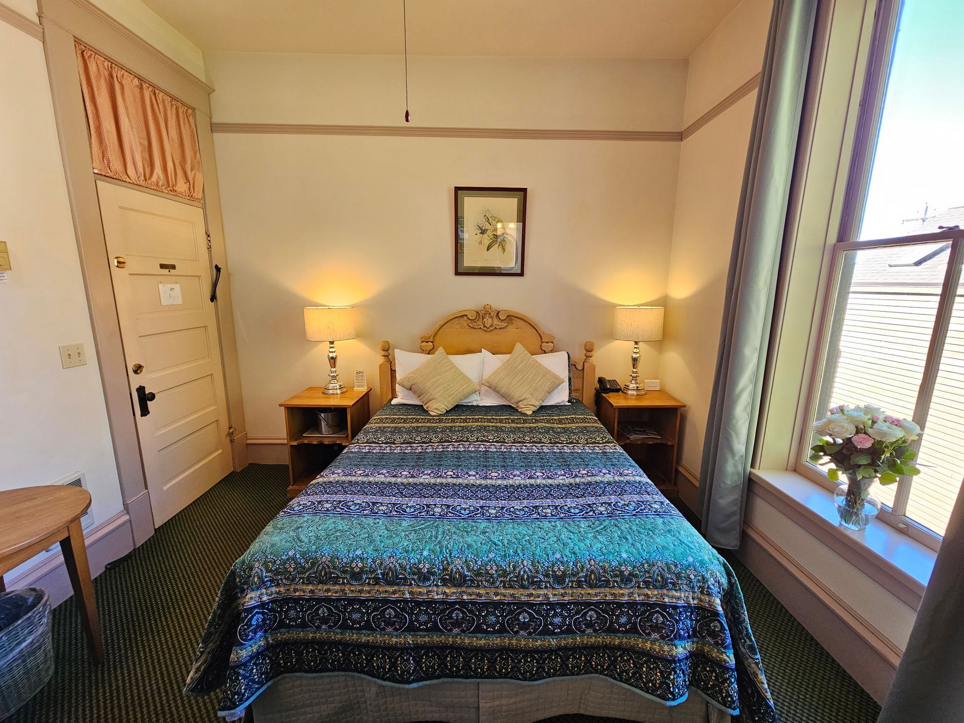 A bedroom with a bed , nightstands , lamps and a window.