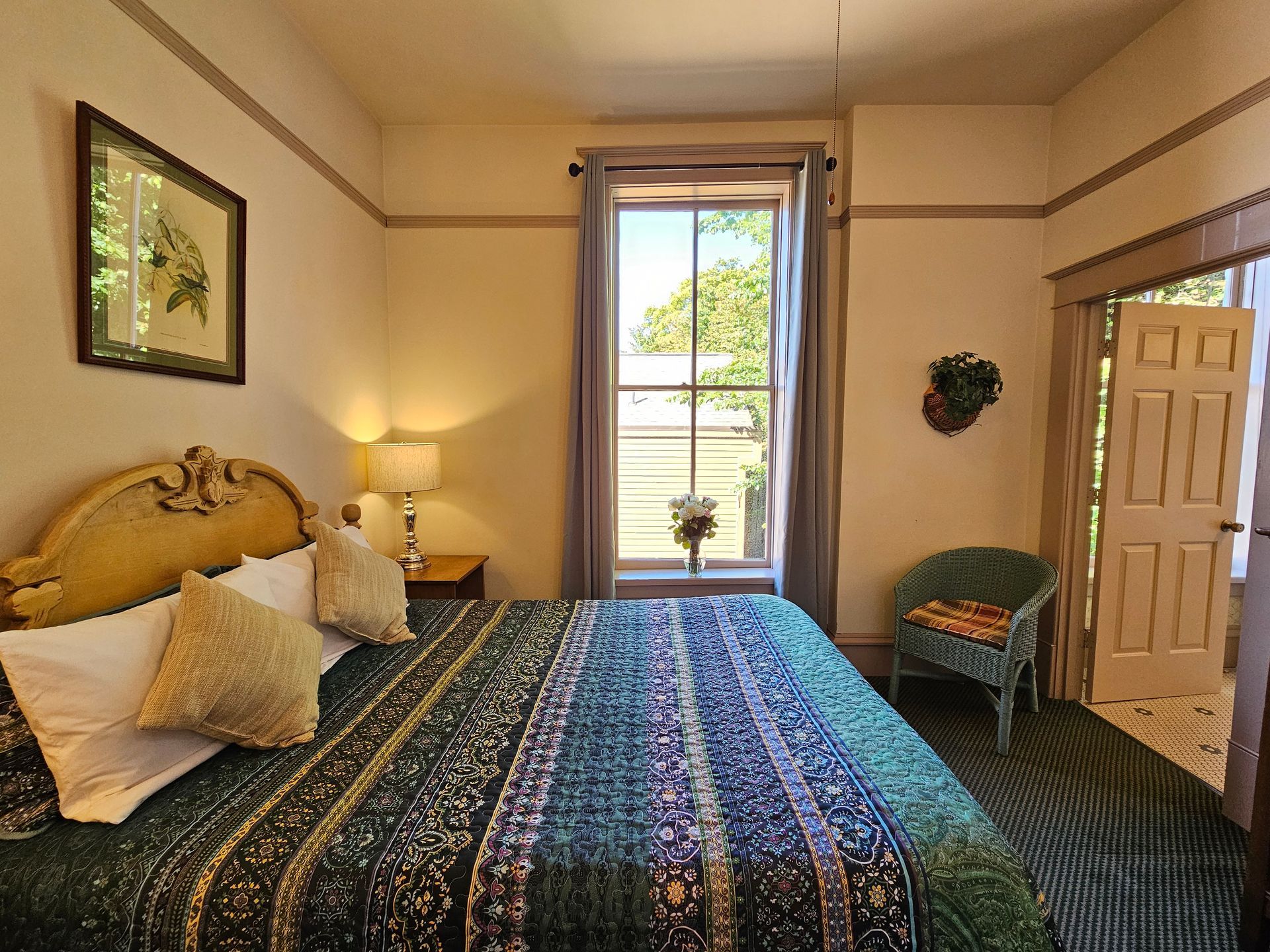 A bedroom with a bed , chair , lamp and window.