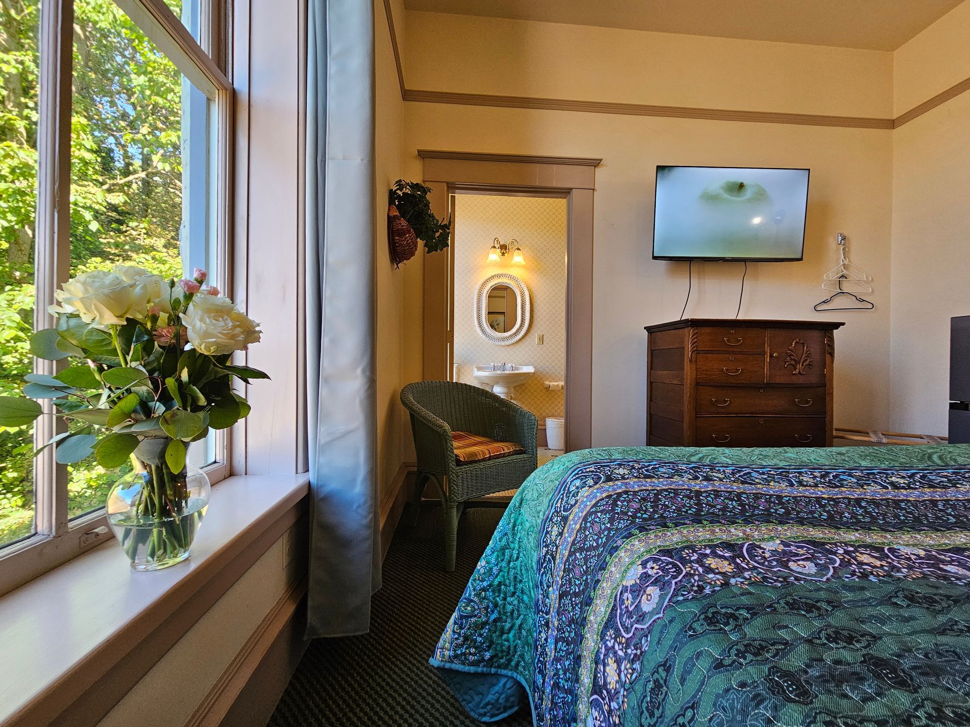 A hotel room with a bed , dresser , chair and television.