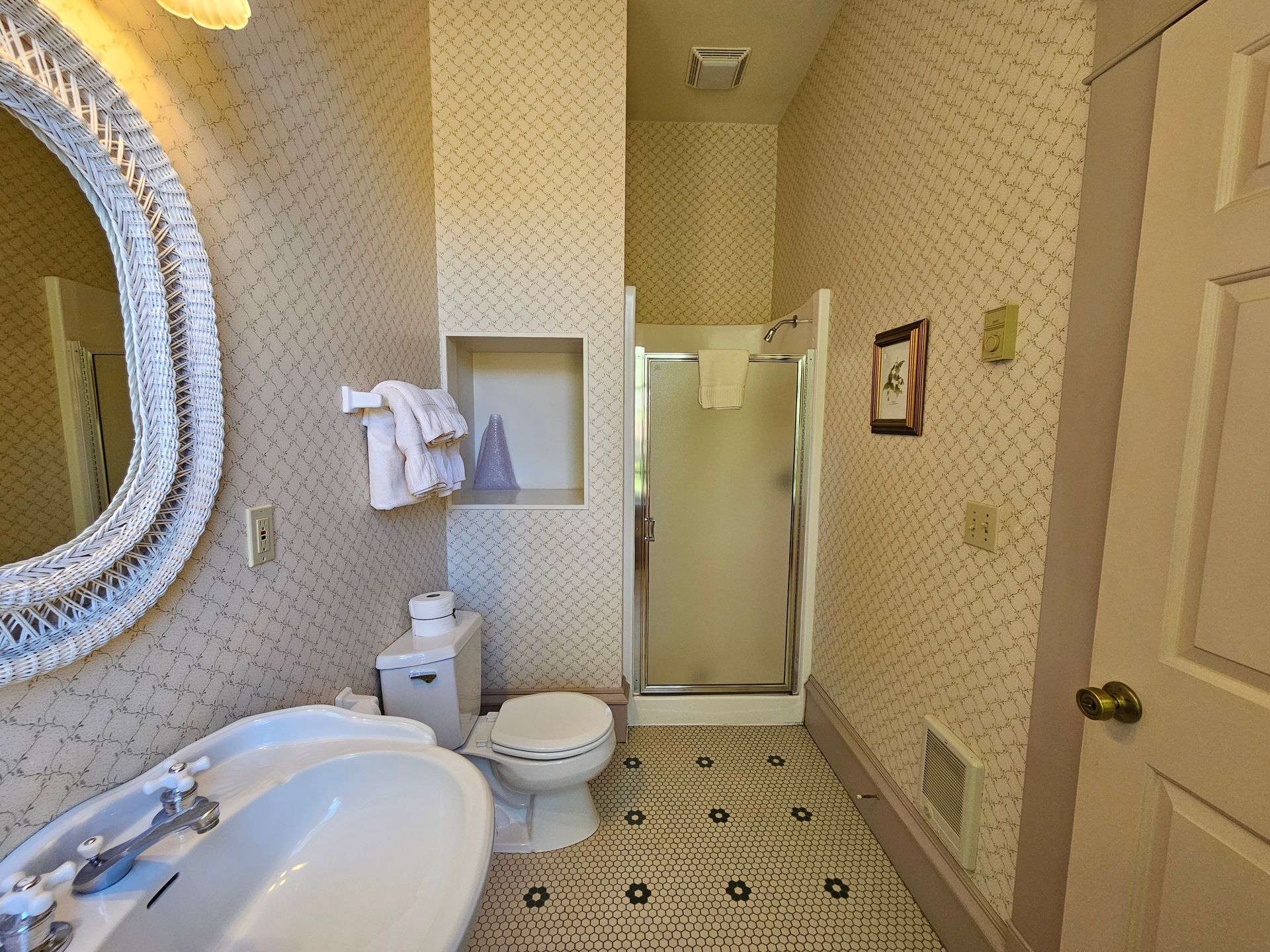 A bathroom with a toilet , sink , mirror and shower.