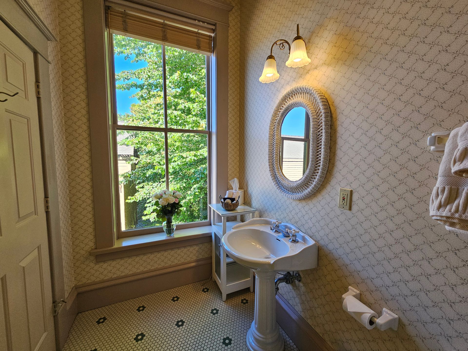 A bathroom with a sink , mirror and window.