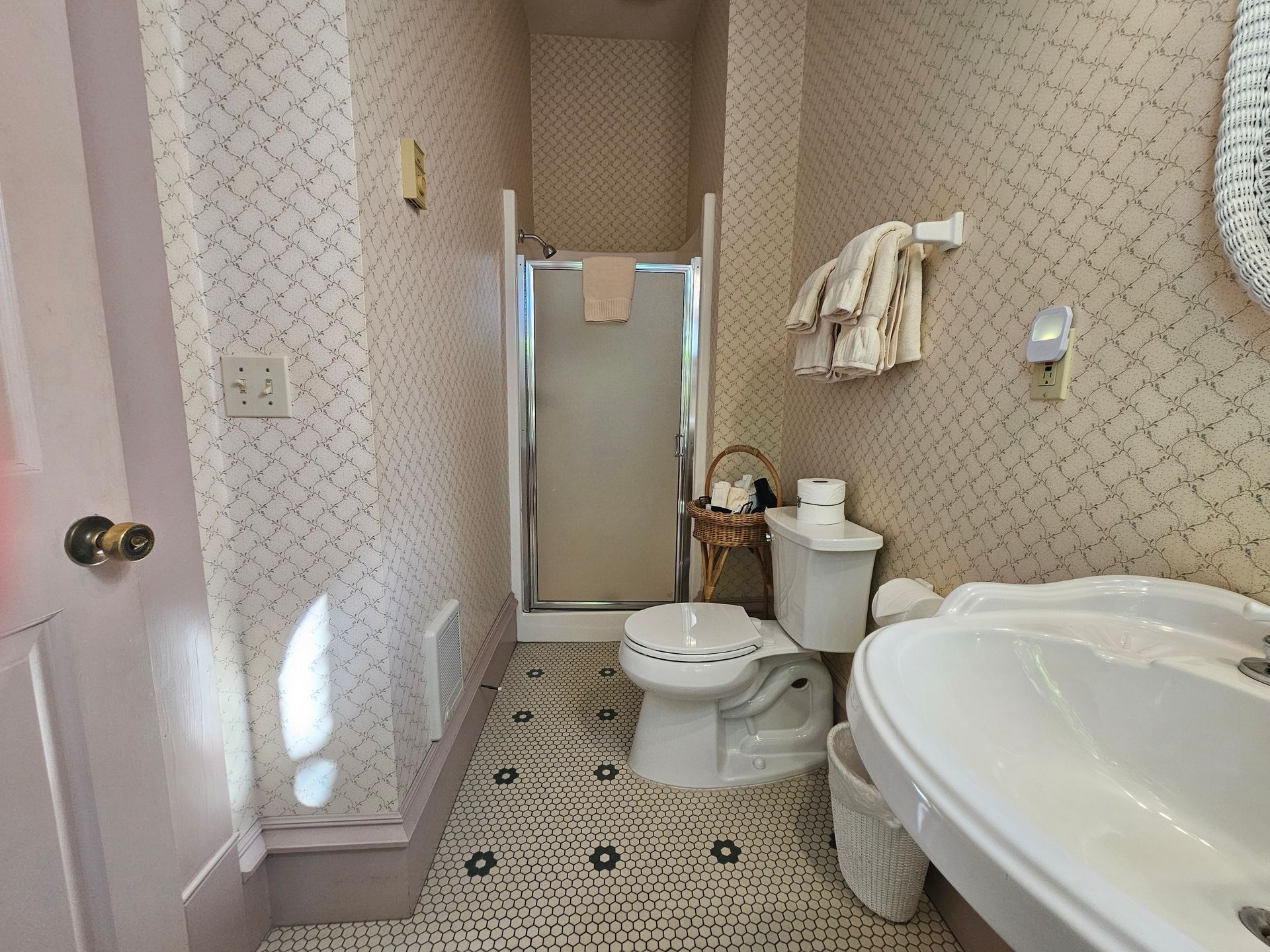 A bathroom with a toilet , sink and shower.