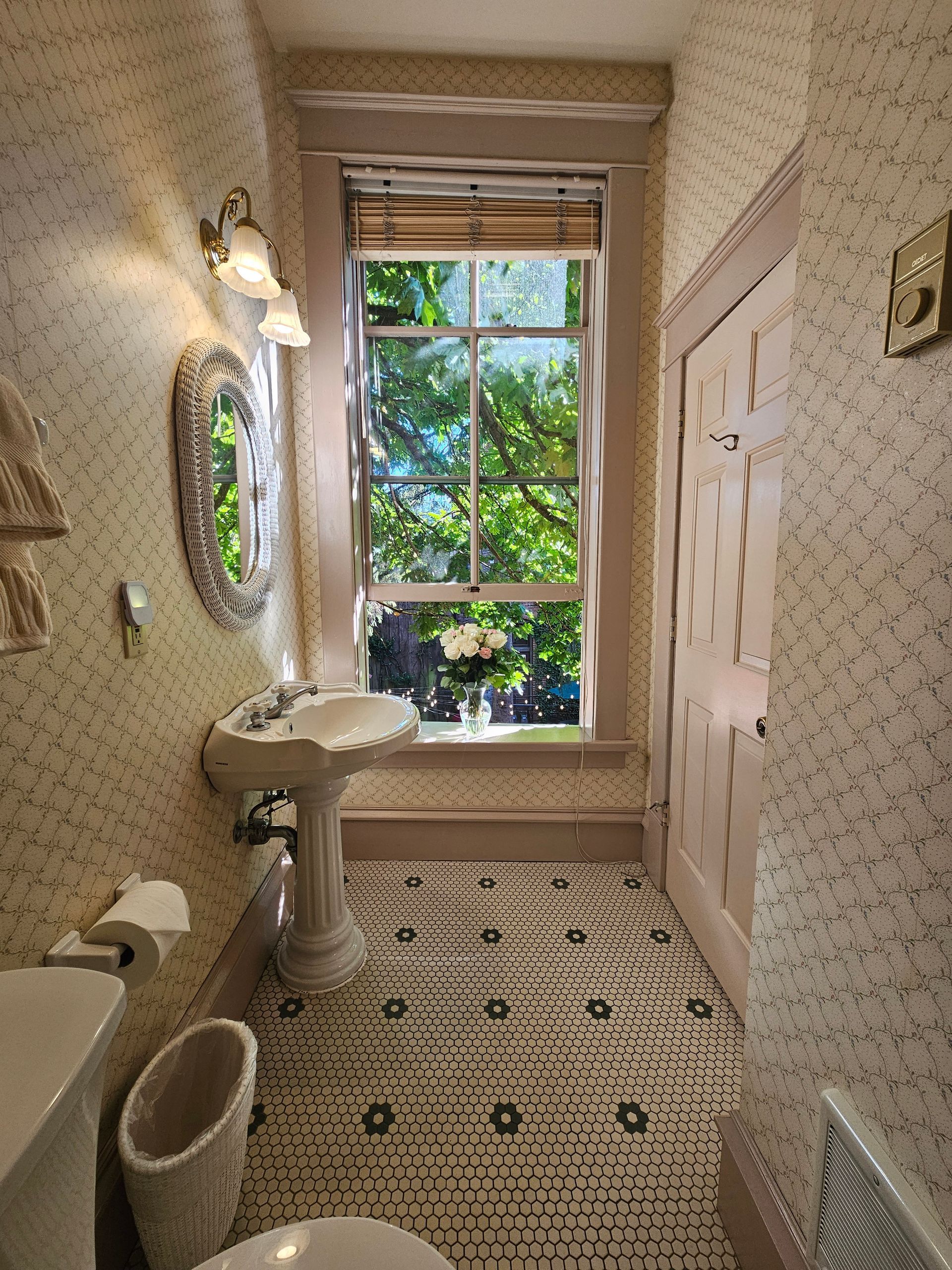 A bathroom with a sink , toilet , mirror and window.