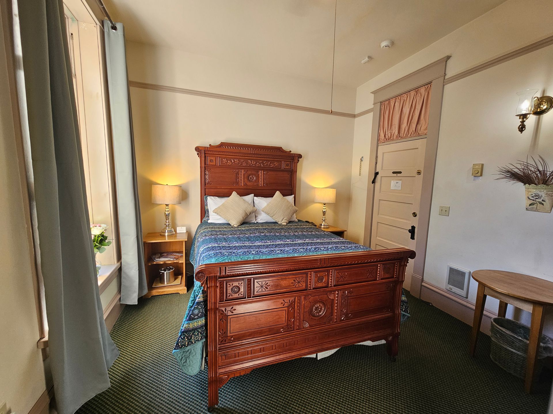 A bedroom with a bed , nightstands , lamps and a window.