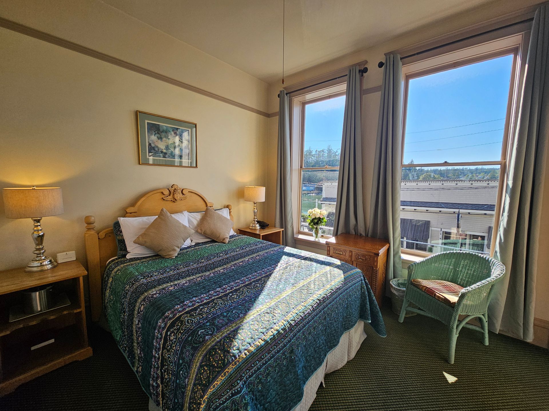 A hotel room with a king size bed and two windows