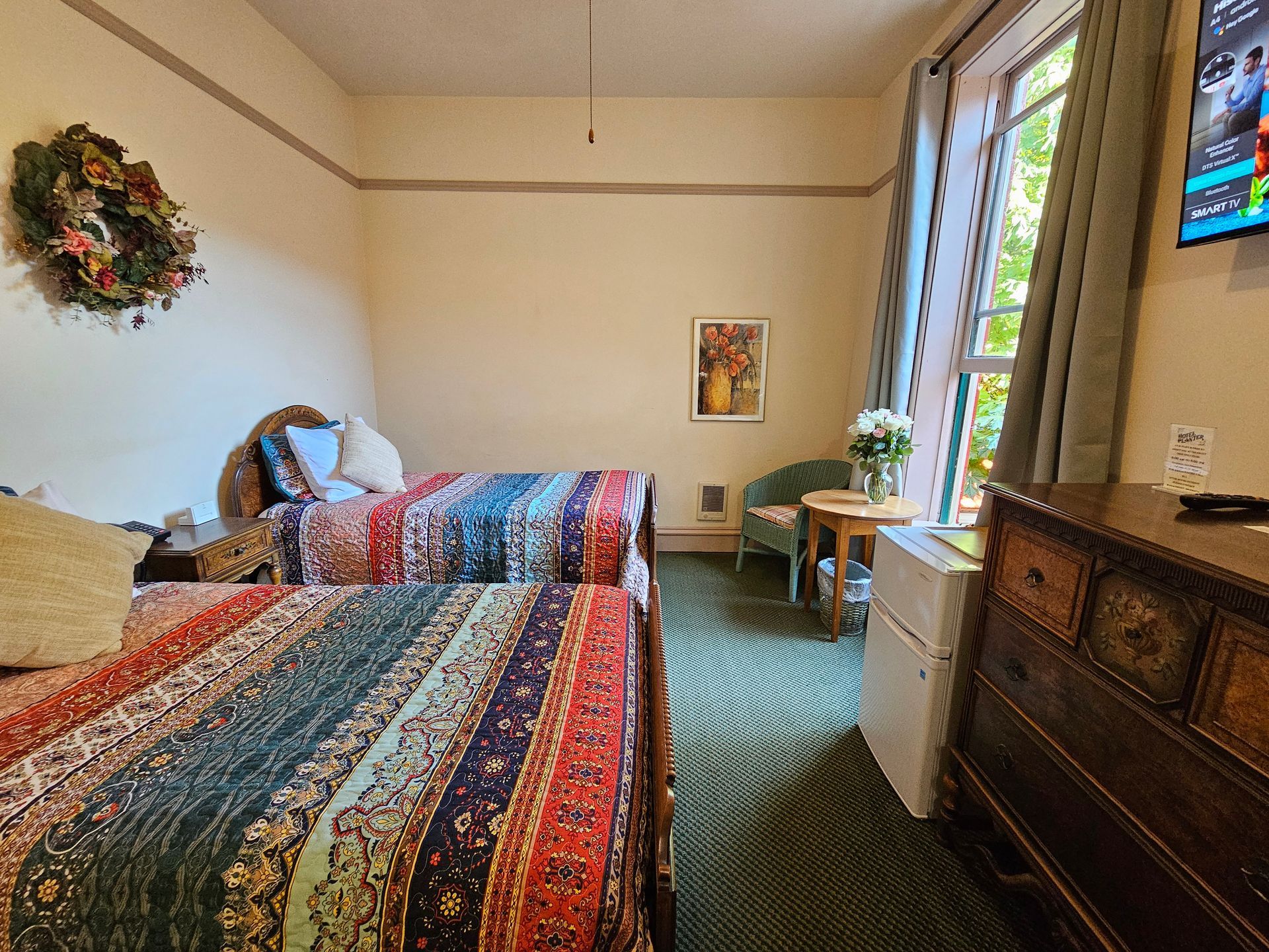 A hotel room with two beds , a dresser and a television.