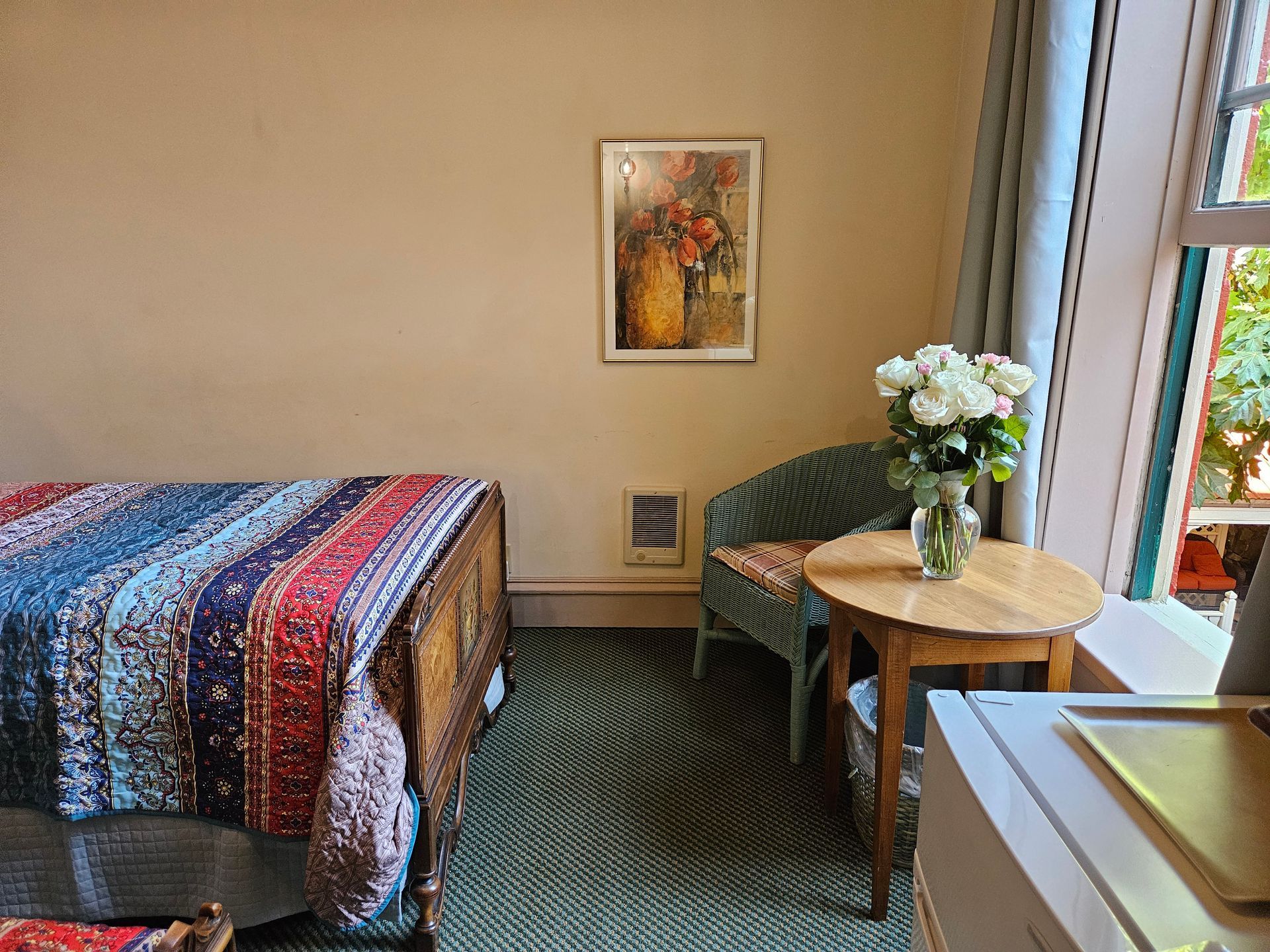 A bedroom with a bed , chair , table and a picture on the wall.