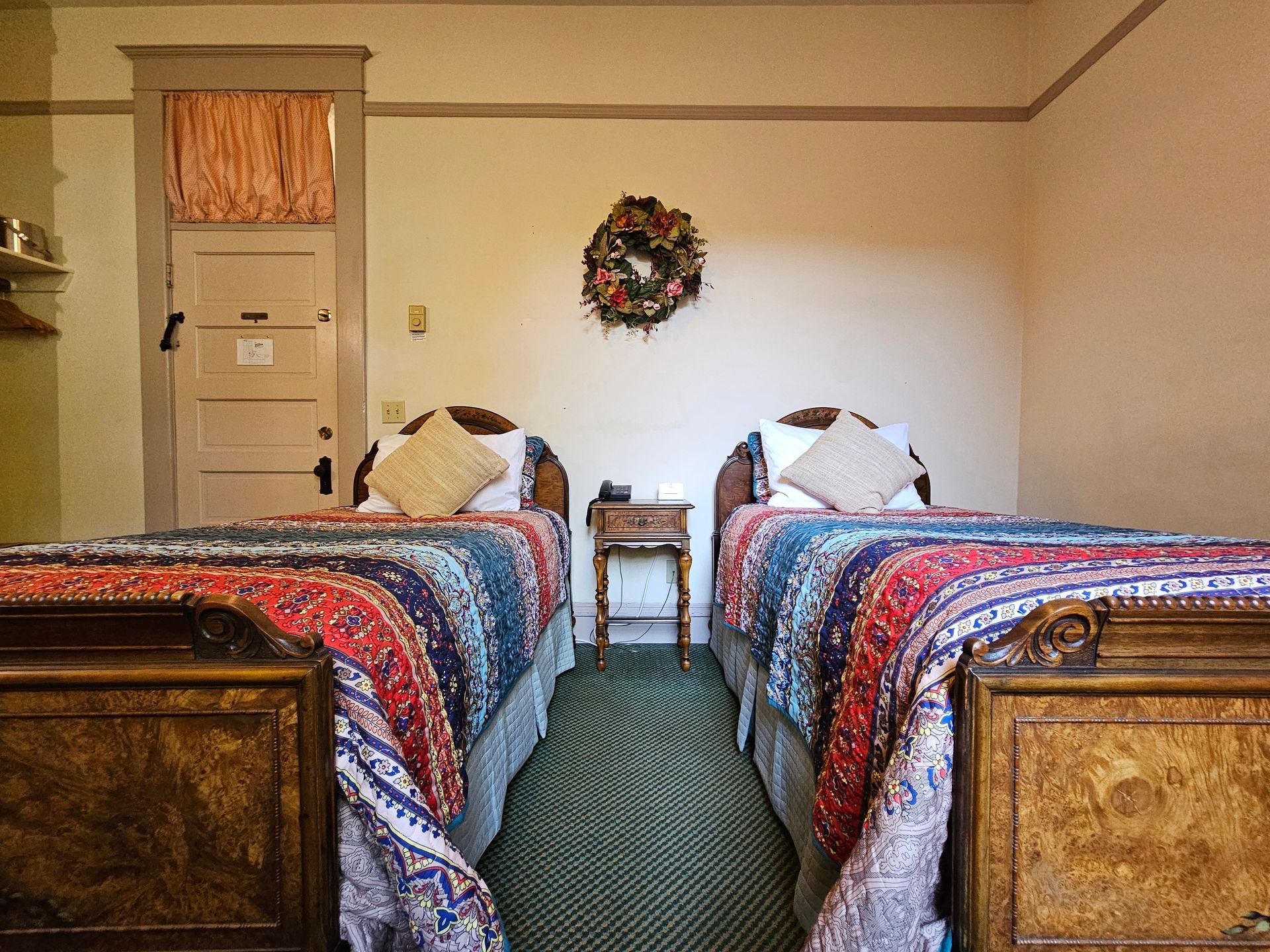 A bedroom with two beds and a wreath on the wall.