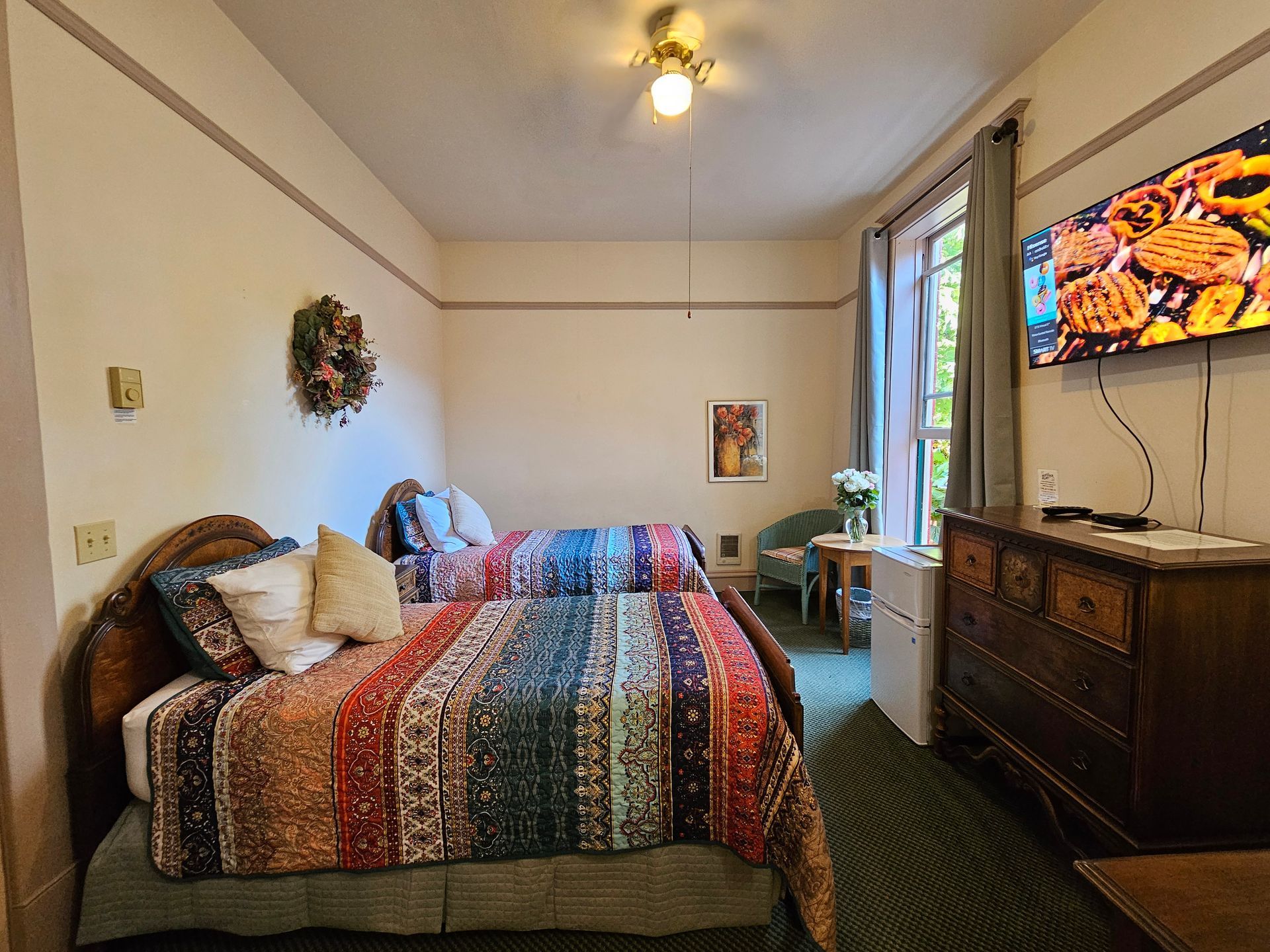 A bedroom with two beds , a dresser , and a flat screen tv.