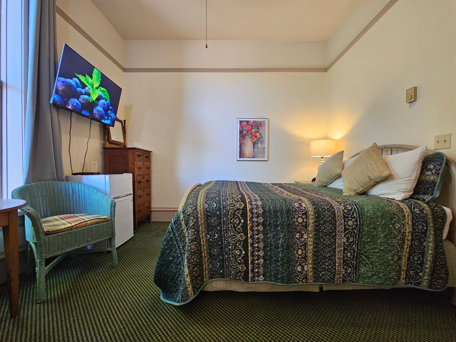 A bedroom with a bed , chair , dresser and television.