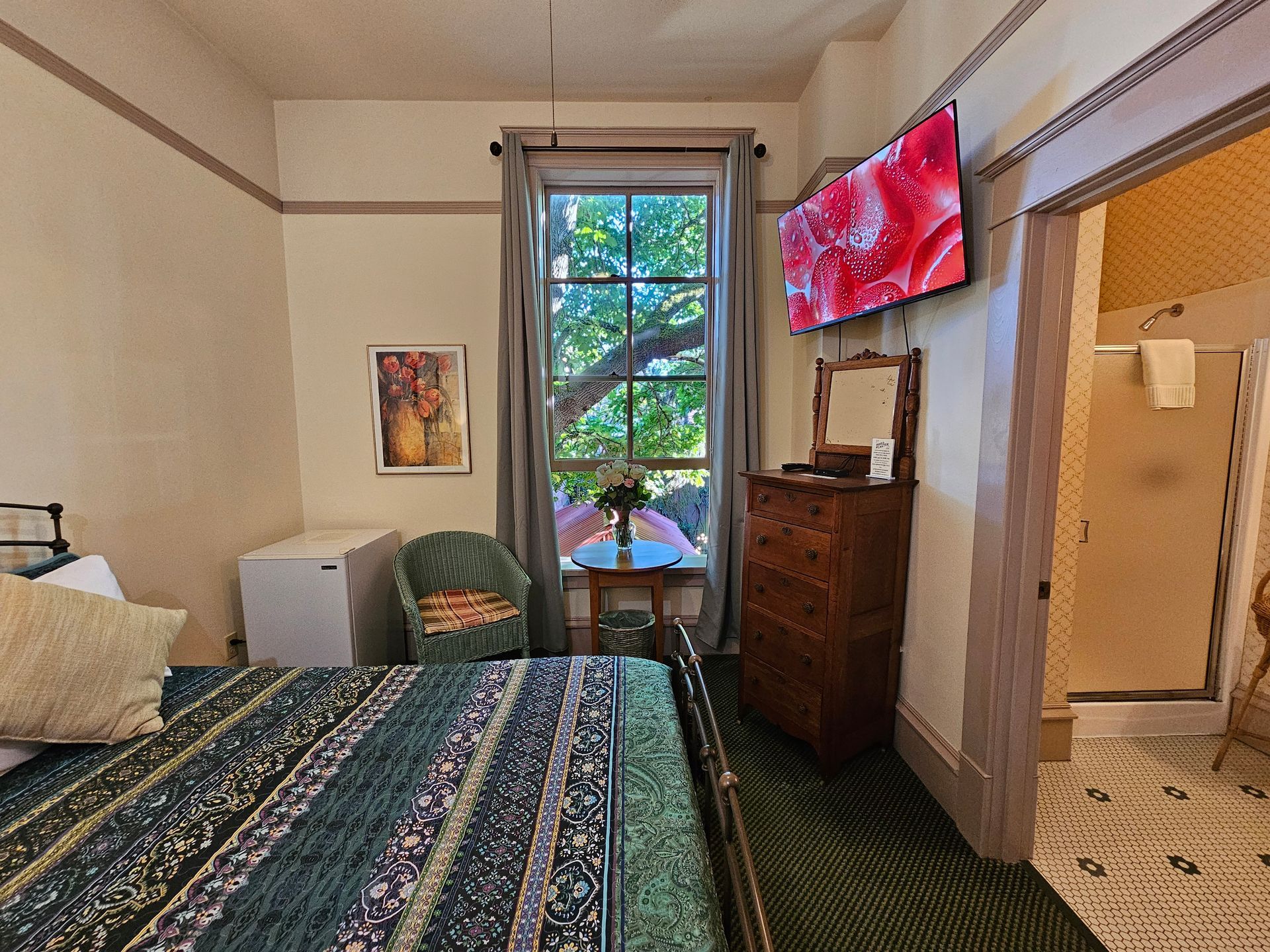 A bedroom with a bed , dresser , chair and television.