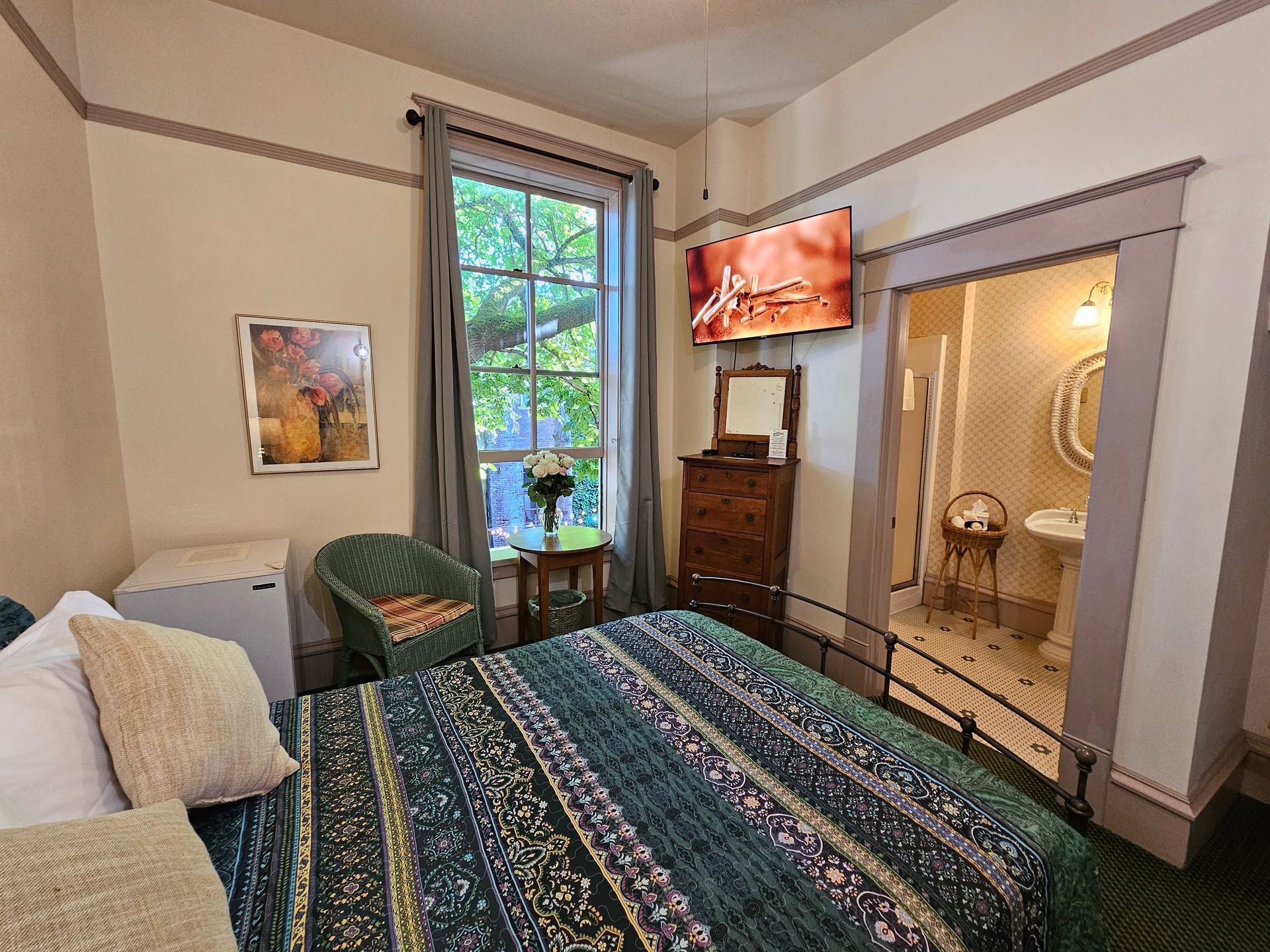 A bedroom with a bed , dresser , chair and television.