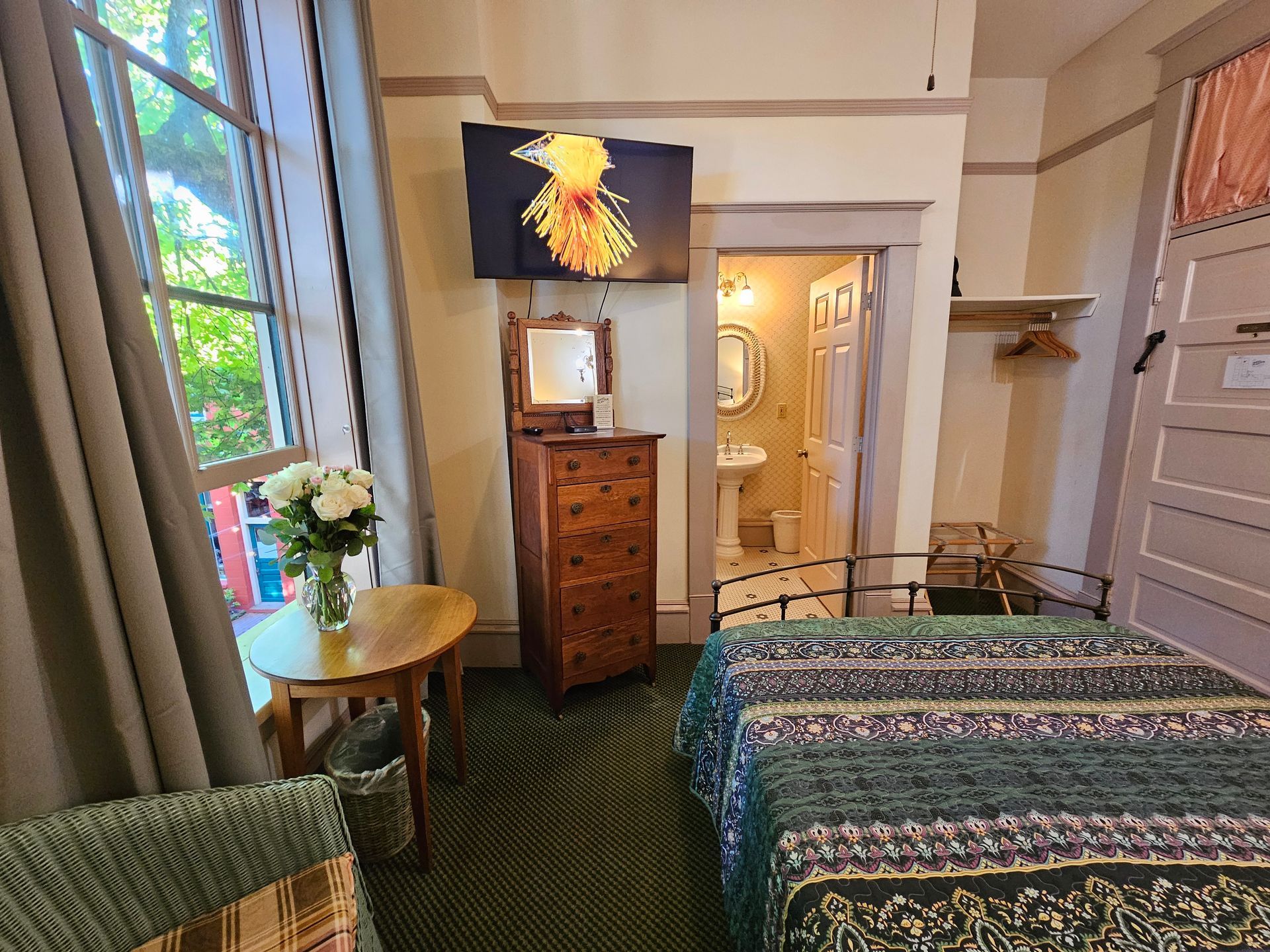 A bedroom with a bed , dresser , table and television.