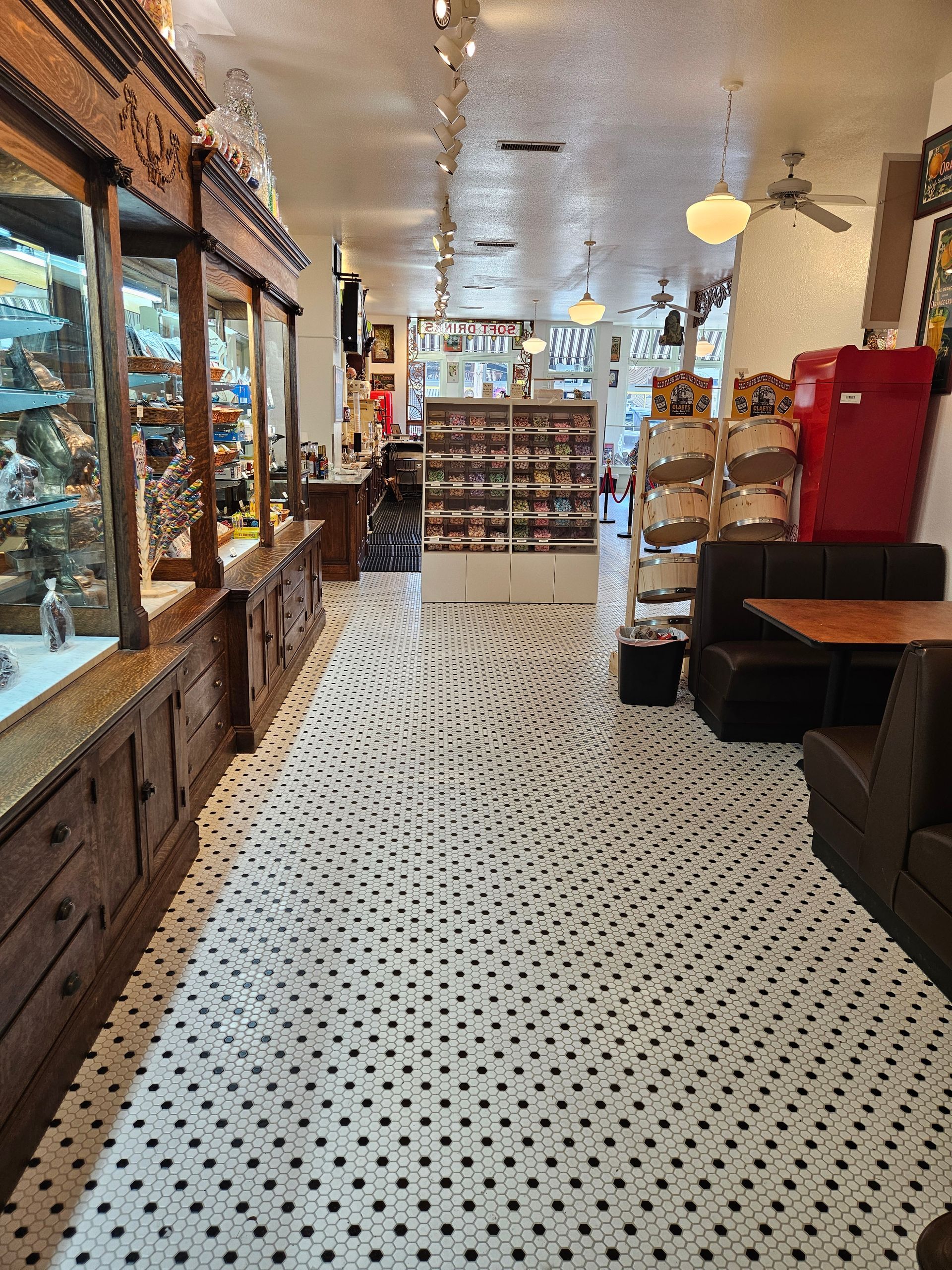 A long hallway in a bakery with tables and chairs.