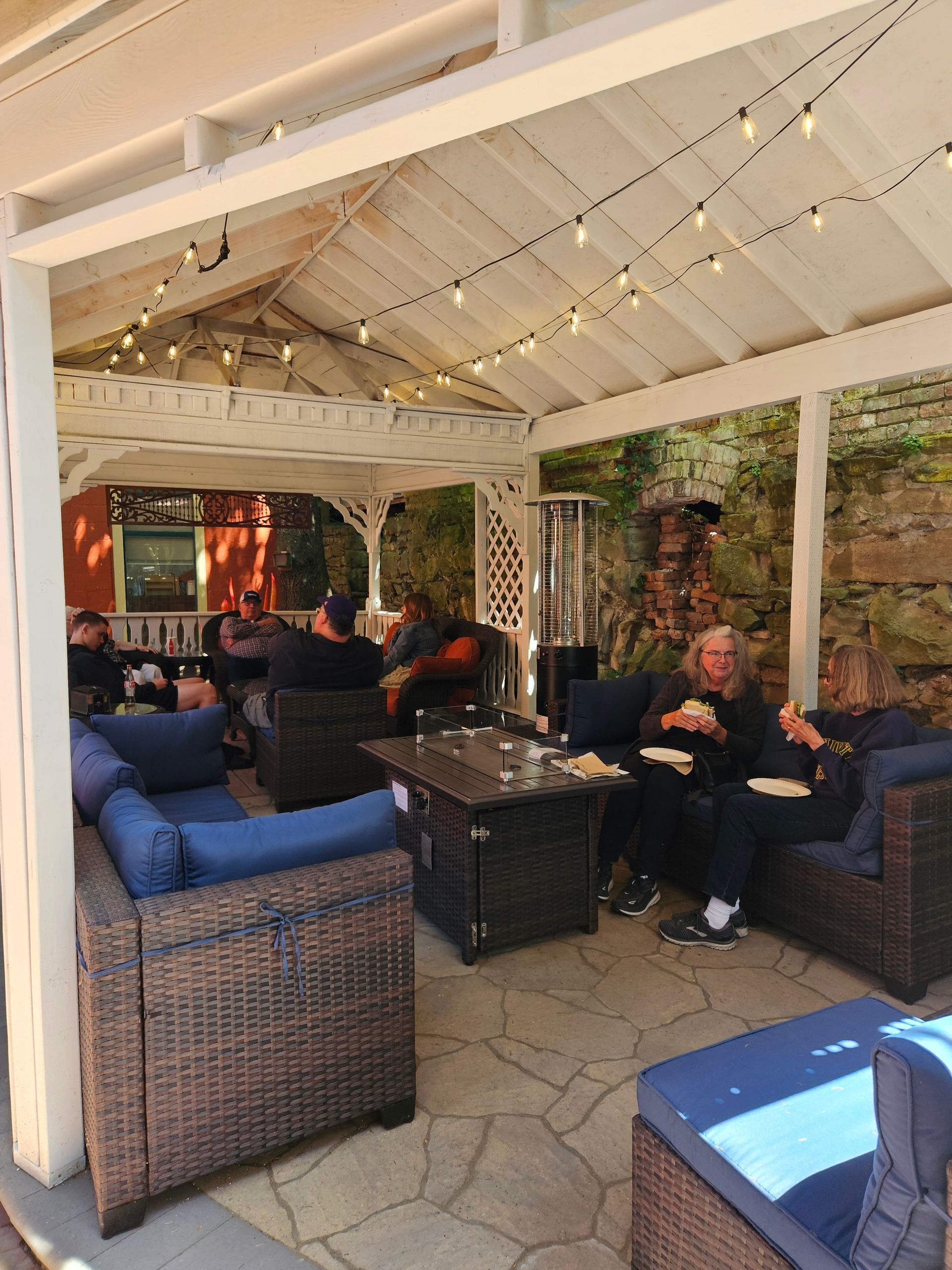 A group of people are sitting in a gazebo eating pizza.