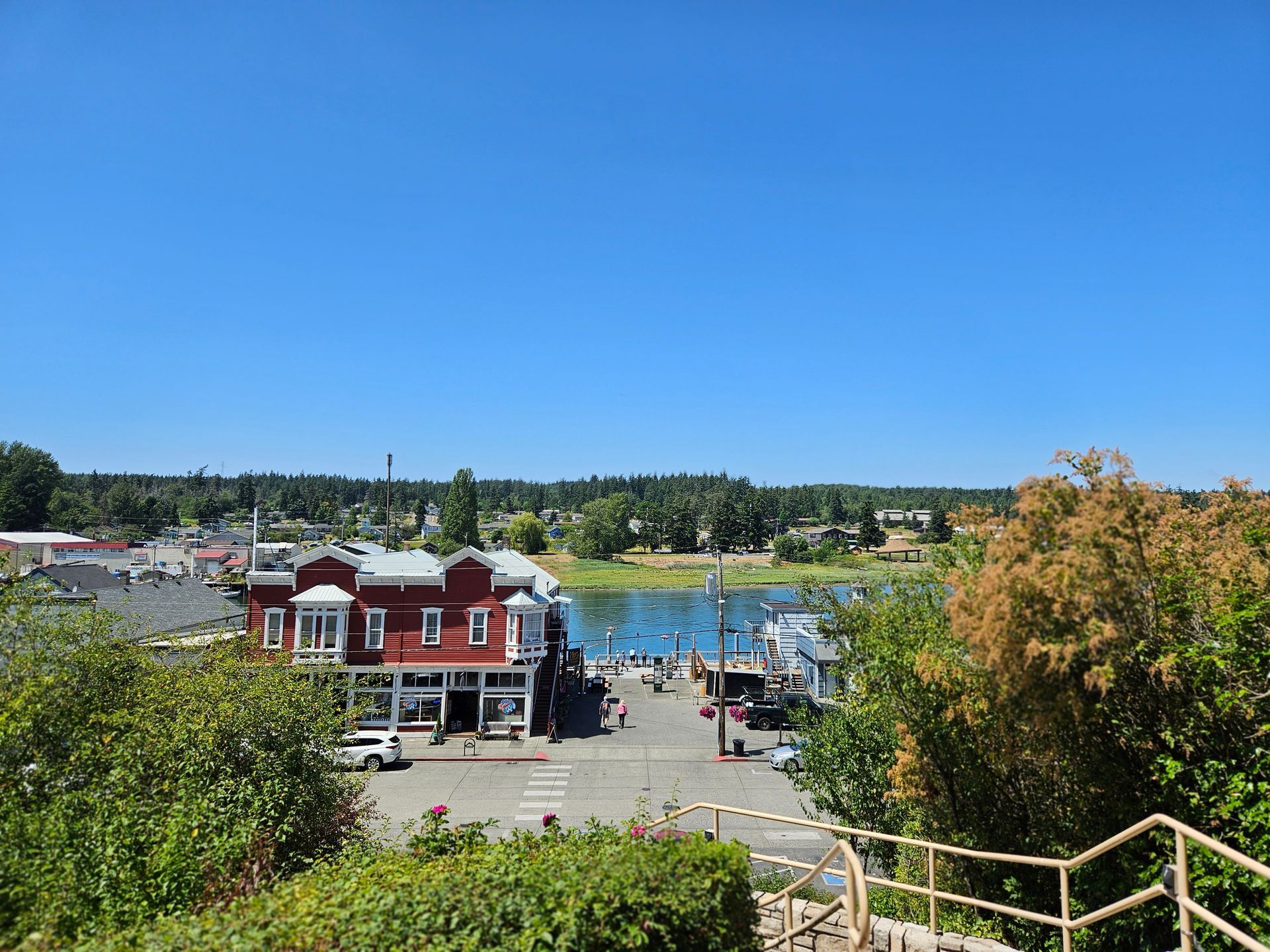 An aerial view of a small town with a red building in the foreground and a body of water in the background.