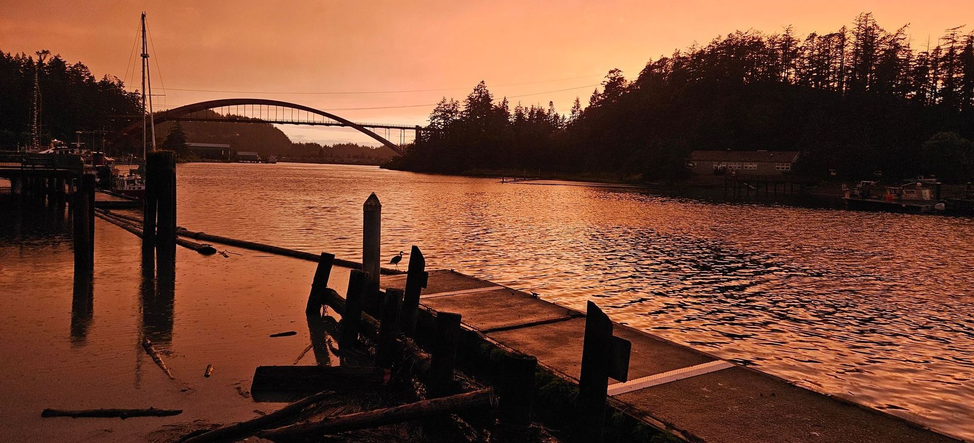 A sunset over a river with a bridge in the background